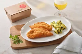 Wiener Schnitzel vom Huhn mit Petersilienkartoffeln auf einem Holzbrett arrangiert, dazu ein Glas Bier