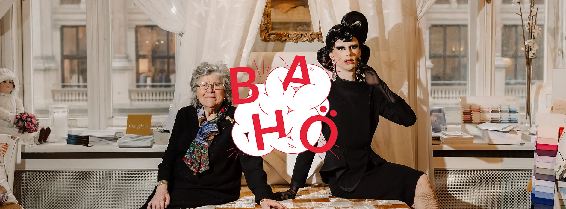 Ältere Dame und Dragqueen sitzen auf einem Bett, im Vordergrund Logo des Podcasts Bahö