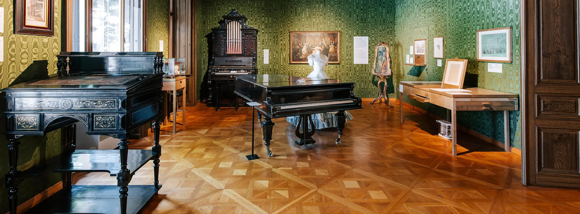 Grüner Salon in der Strauss-Wohnung mit Notenpult, Klavier und Geigenkasten
