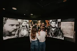 Exhibition space with a huge curved screen on which Strauss portraits can be seen.