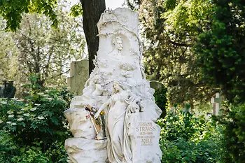 Tumba de mármol de Johann Strauss Sohn con su cabeza en relieve, además de una figura femenina, un murciélago y un ángel tocando el violín en el imponente monumento.