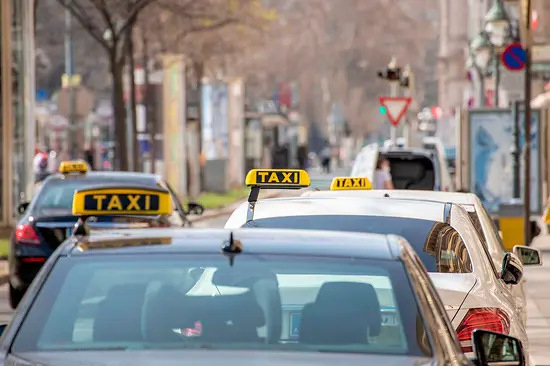 Taxistand in Wien an der Ringstraße mit mehreren Taxis mit Schild (schwarz mit gelber Schrift) 